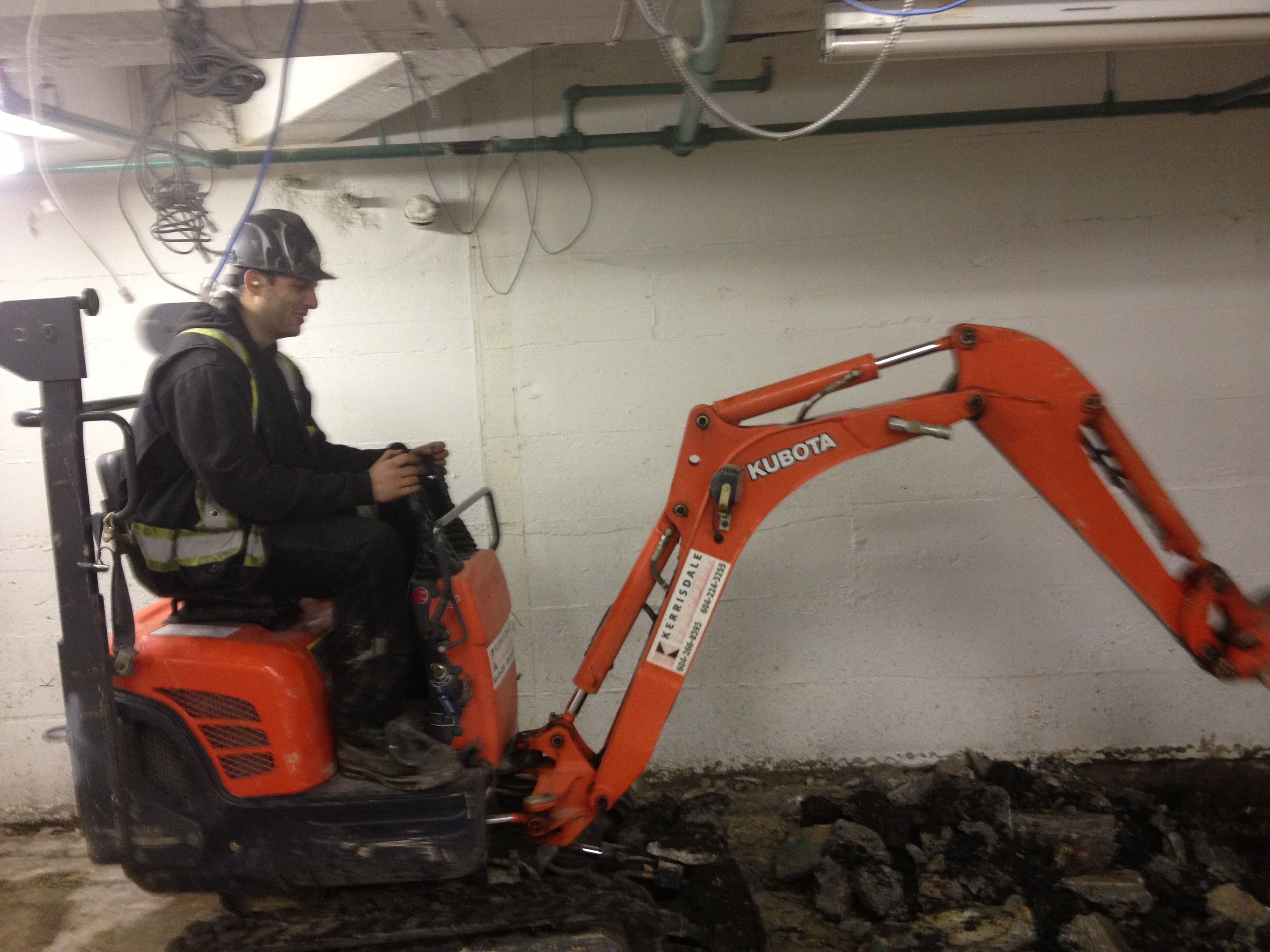 RLW operator running Kubota excavator in basement demolition